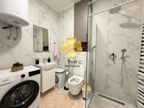 Modernly equipped bathroom with a walk-in shower, washbasin, and washing machine. - image 12