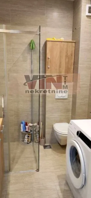 Kupatilo sa tuš kabinom, WC šoljom i veš mašinom.