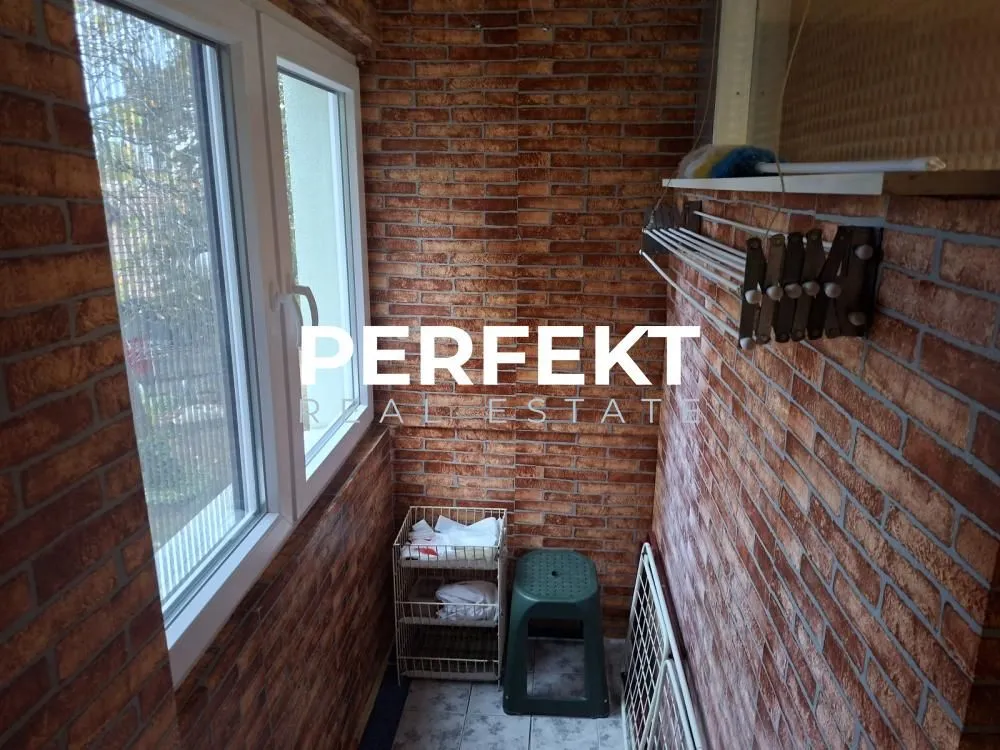 Zastakljeni balkon sa zidovima obloženim ciglom i prozorima sa pogledom spolja.