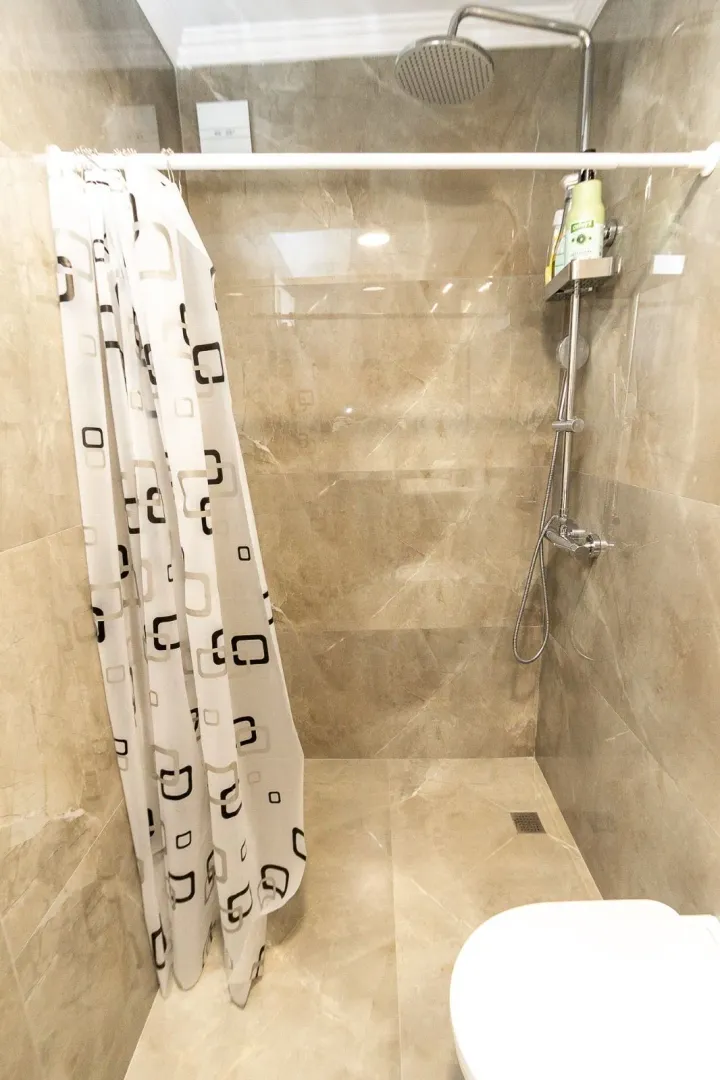 Modern tiles and a shower cabin with a curtain in the bathroom.