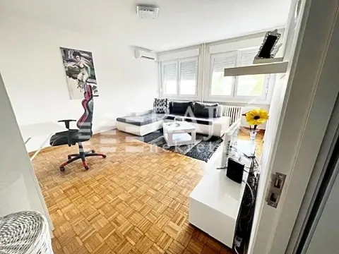 Living room with a sofa, desk, and parquet flooring. - image 5