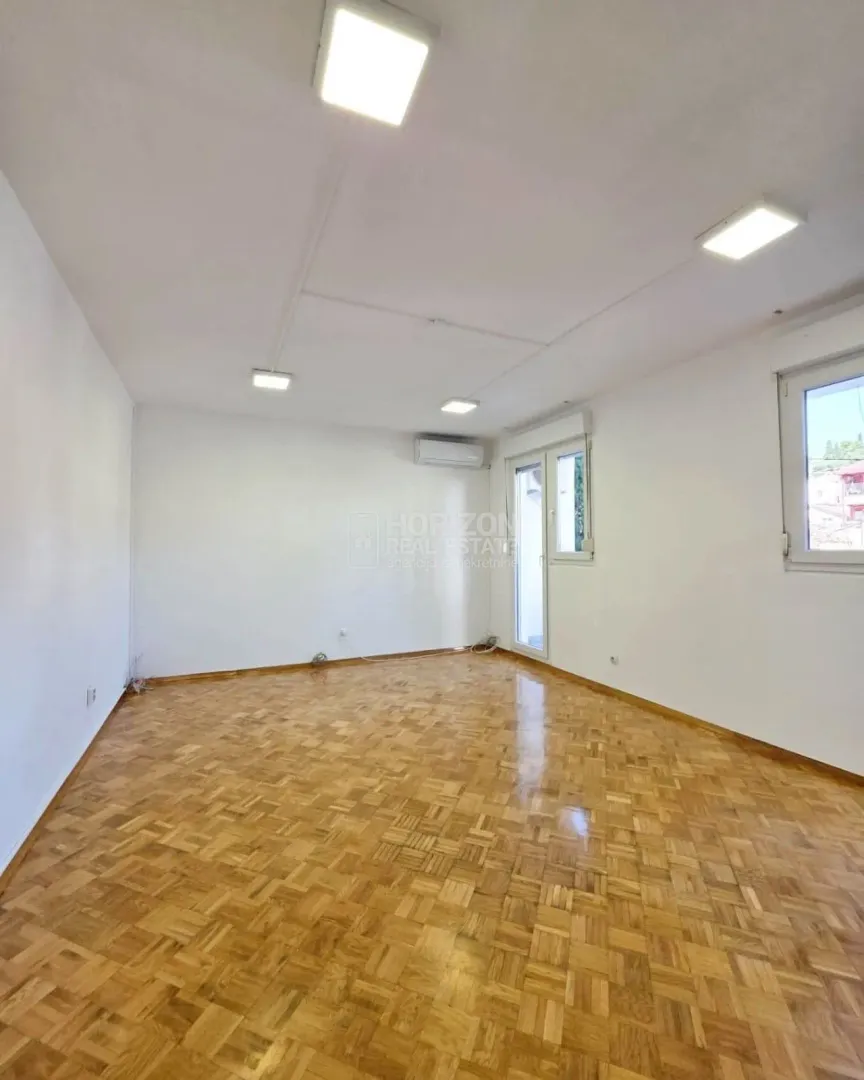 Empty bright room with parquet flooring and white walls.