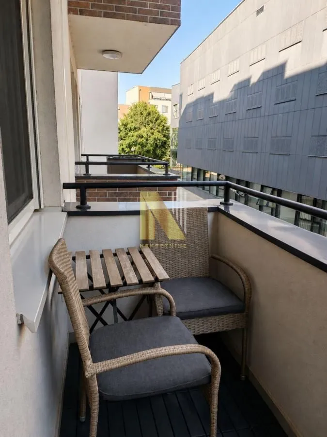 Manji balkon opremljen garniturom za sedenje.