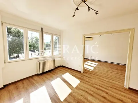 Empty living room with wooden flooring and large windows. - image 4
