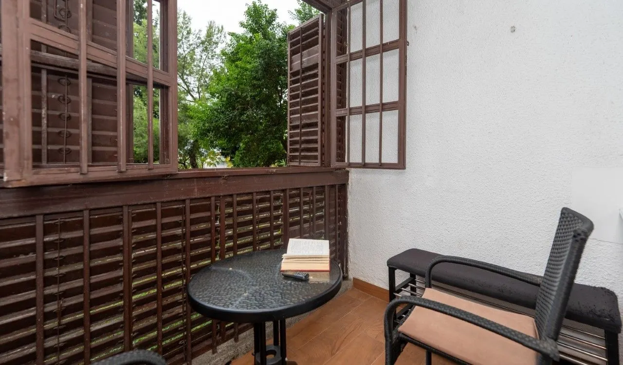 Furnished balcony with a table, chairs, and a view of greenery.