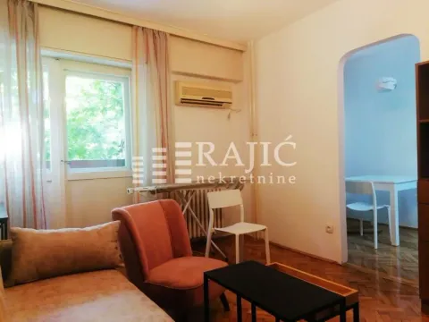 Living room with an armchair, coffee table, and a view of the dining area. - image 2
