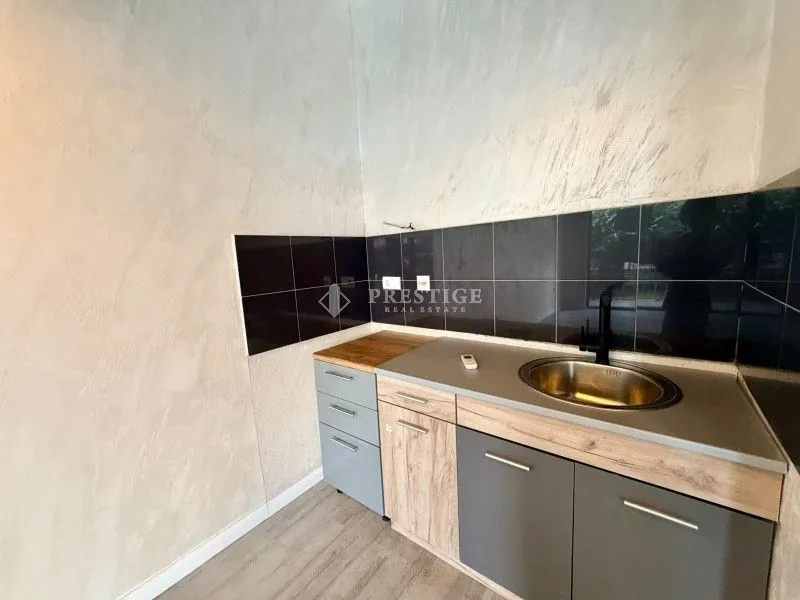 Smaller kitchen with a sink and lower cabinets in silk and wood tones.