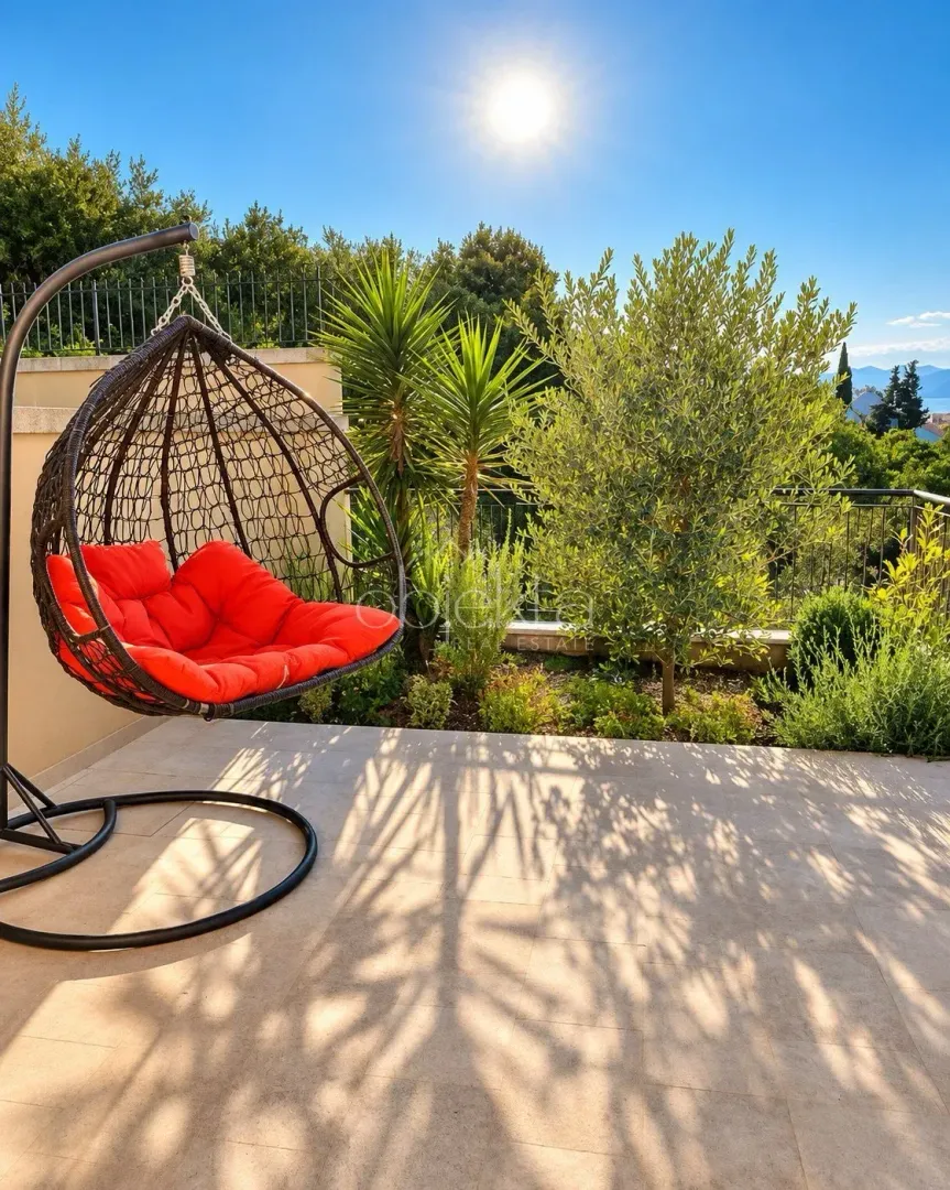 Terrace with a hanging chair and landscaped greenery.