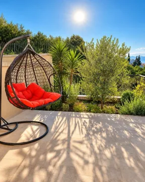 Terrace with a hanging chair and landscaped greenery. - image 4