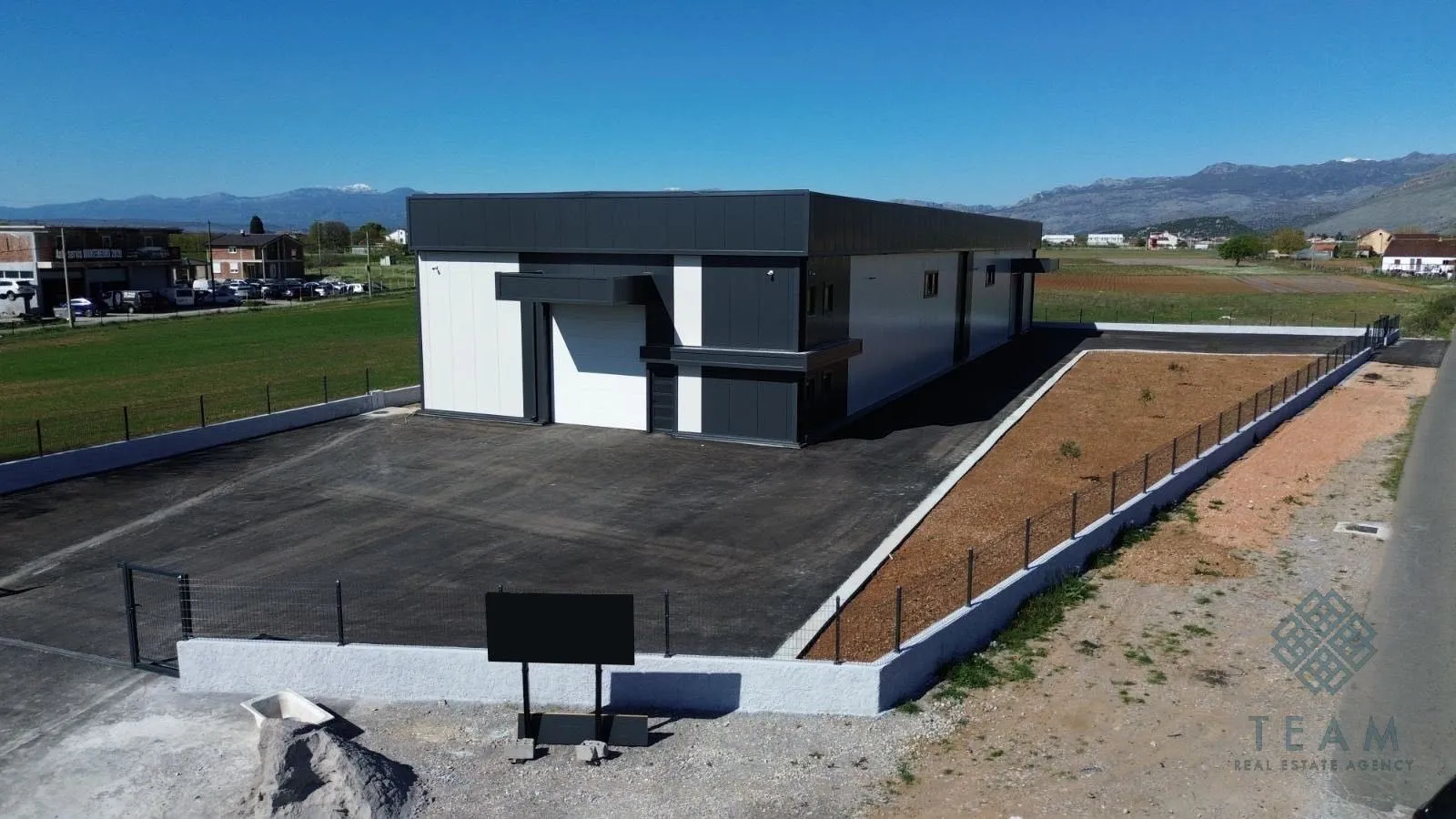 Aerial view of a newly built commercial building with its own courtyard and parking lot.