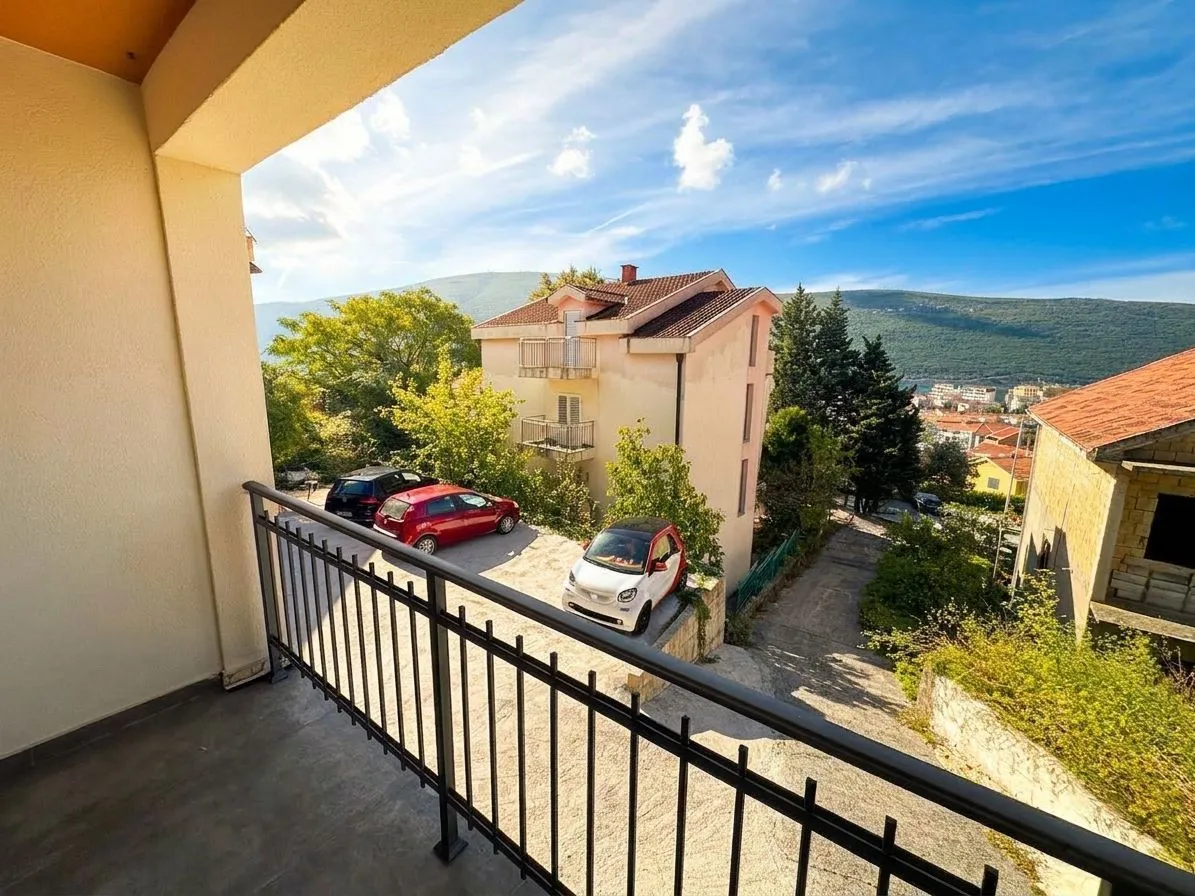 Pogled sa balkona na dvorište, okolne zgrade i brda.