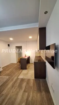 Dugačka kuhinja sa tamnim elementima i šankom za ručavanje. - image 10
