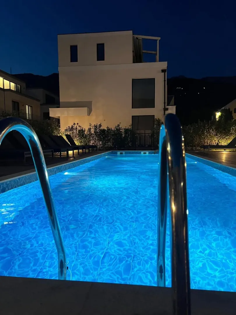 Noćni pogled na osvijetljeni bazen i fasadu zgrade.
