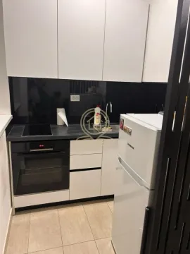 Small kitchen with white cabinets, built-in oven, and refrigerator. - image 6