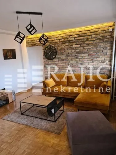 Living room with a sectional sofa, brick wall, and modern lighting.