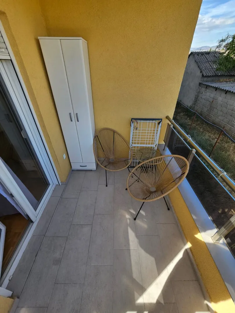 Manji natkriveni balkon sa garniturom za sjedenje i ormarom.