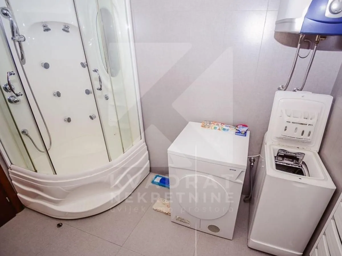 Bathroom with a shower cabin and washing machines.