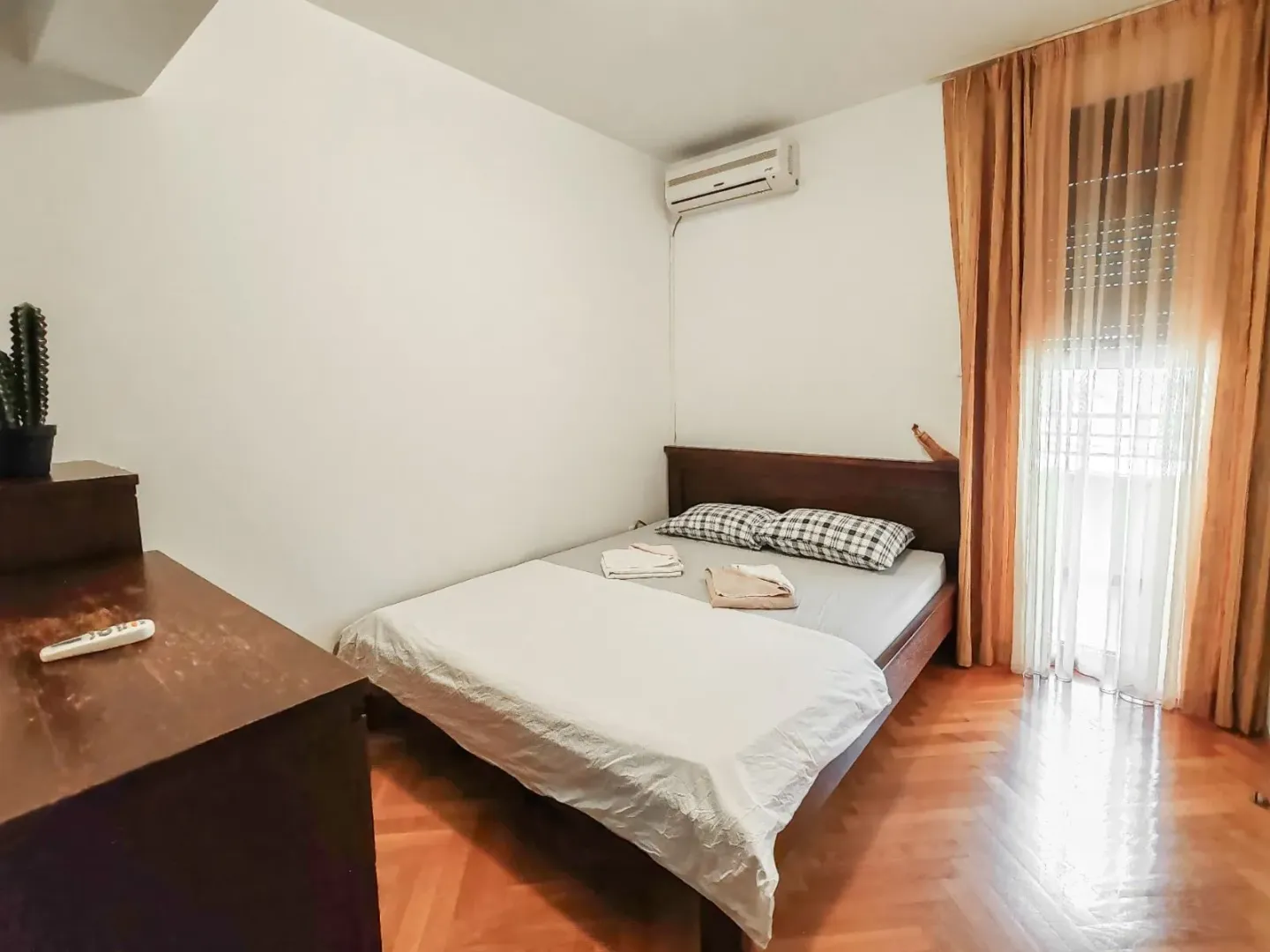 Bedroom with a double bed, wooden parquet flooring, and an air conditioning unit.