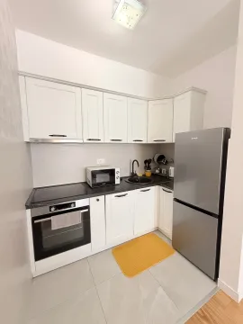 Bijela kuhinja sa ugradnim elementima i frižiderom. - image 3