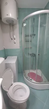 A bathroom featuring a shower cabin, water heater, and washing machine. - image 8