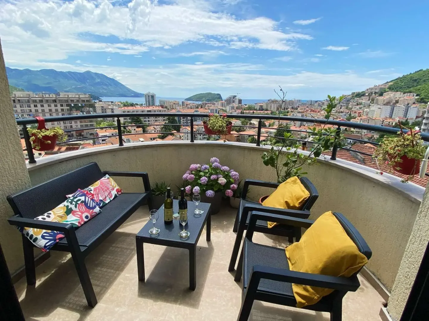 Furnished balcony with outdoor seating and a view of the city and the sea.