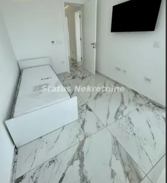 Manja spavaća soba sa krevetom i televizorom na zidu. - image 16
