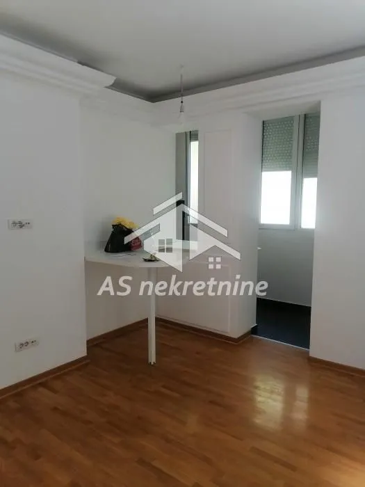 Manja kuhinja sa ugrađenim pultom i drvenim podom.
