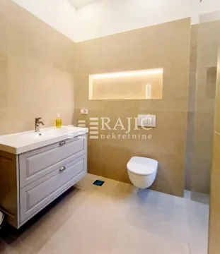 Modernly equipped bathroom with a vanity and built-in toilet. - image 18