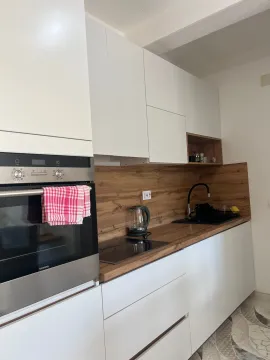Modern white kitchen with wooden elements and a built-in oven. - image 7