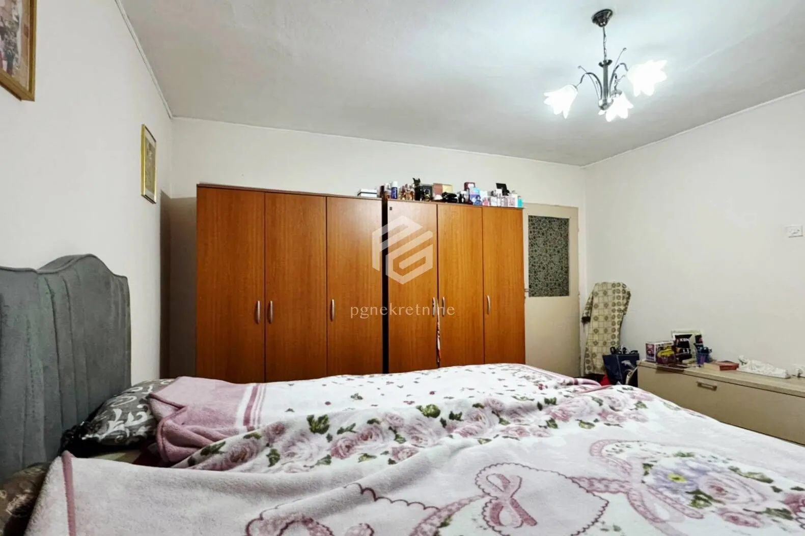 Spavaća soba sa bračnim krevetom i drvenim ormarom.