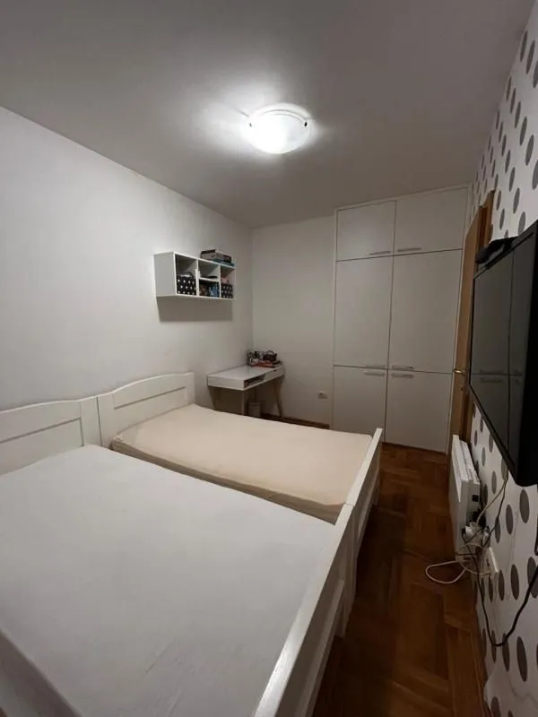 Spavaća soba sa dva kreveta, ormarom i televizorom.