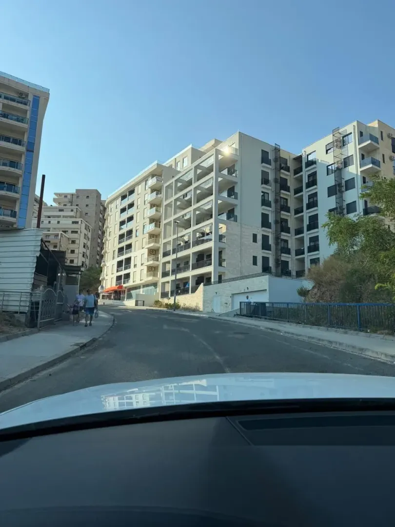 Pogled iz automobila na novu stambenu zgradu i ulicu.