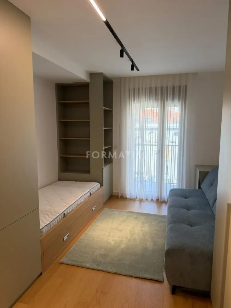 Smaller bedroom with a bed, built-in wardrobes, and a sofa.