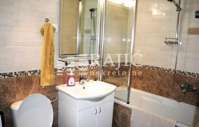 Small bathroom with a sink, shower cabin, and sanitary fixtures.