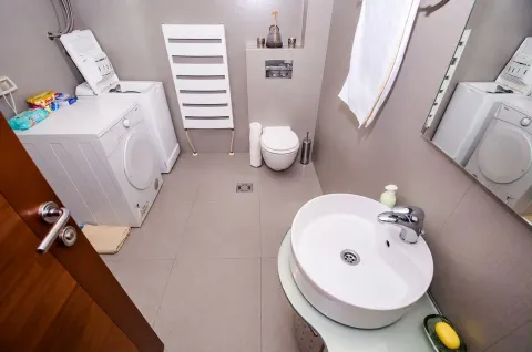 Modern bathroom with a washbasin, toilet, and washing machine. - image 10