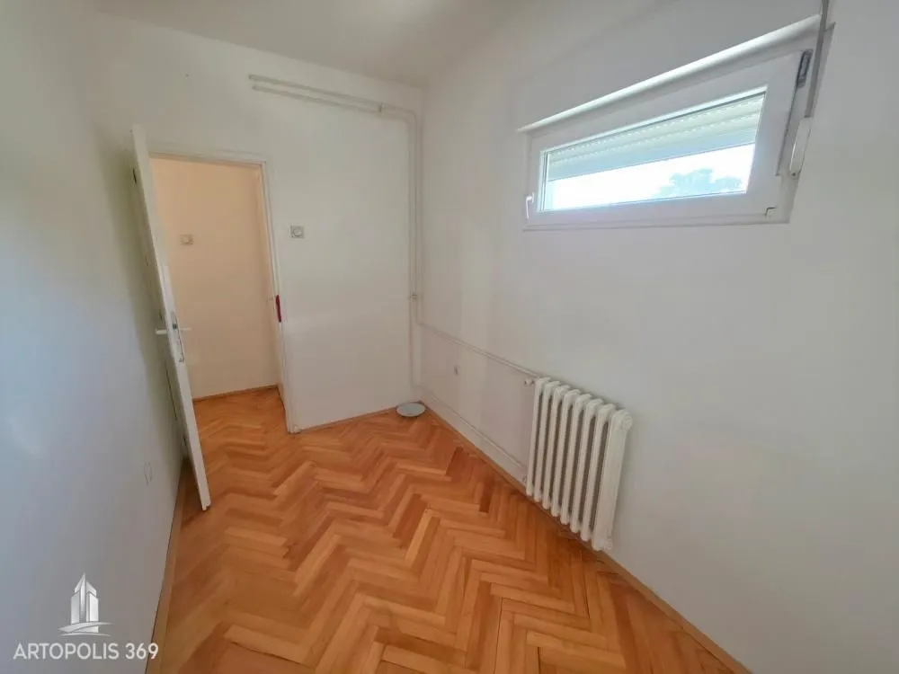 Prazna soba sa parketom i radijatorom.