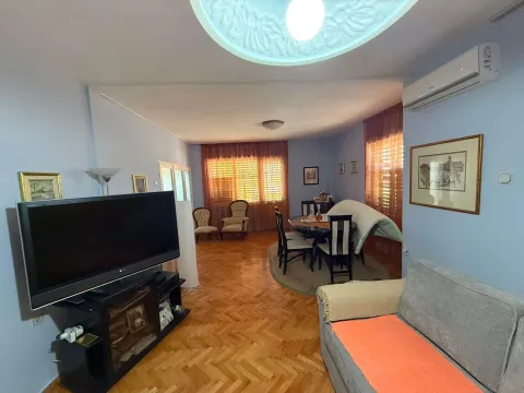 Spacious living room with a sofa, TV, and dining area. - image 6