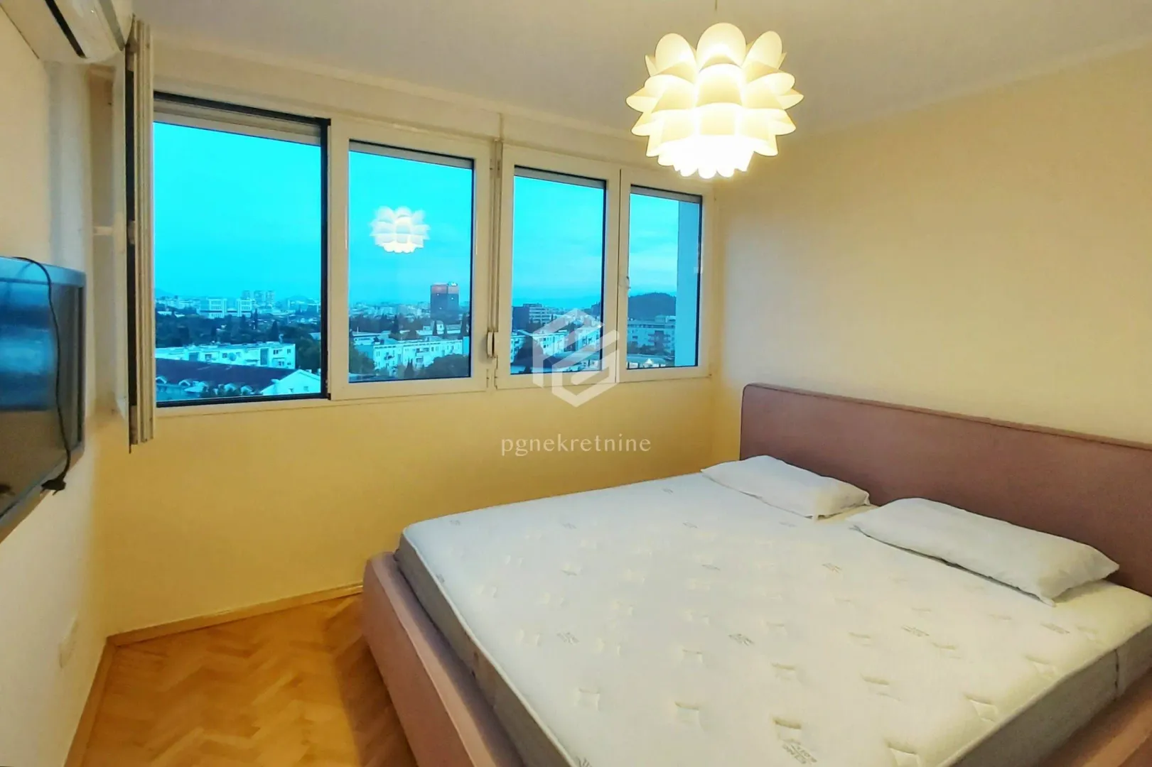 Bedroom with a double bed and windows overlooking the city.