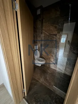 Moderno opremljeno kupatilo sa tamnim mermernim pločicama i tuš kabinom. - image 7