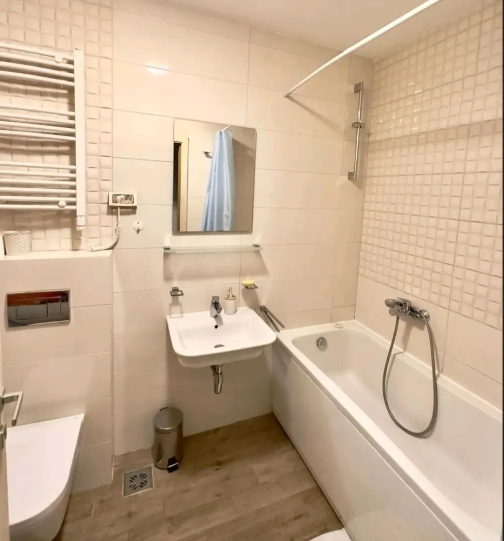 Brightly furnished bathroom with a bathtub, sink, and toilet.