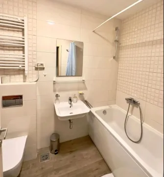 Brightly furnished bathroom with a bathtub, sink, and toilet. - image 4