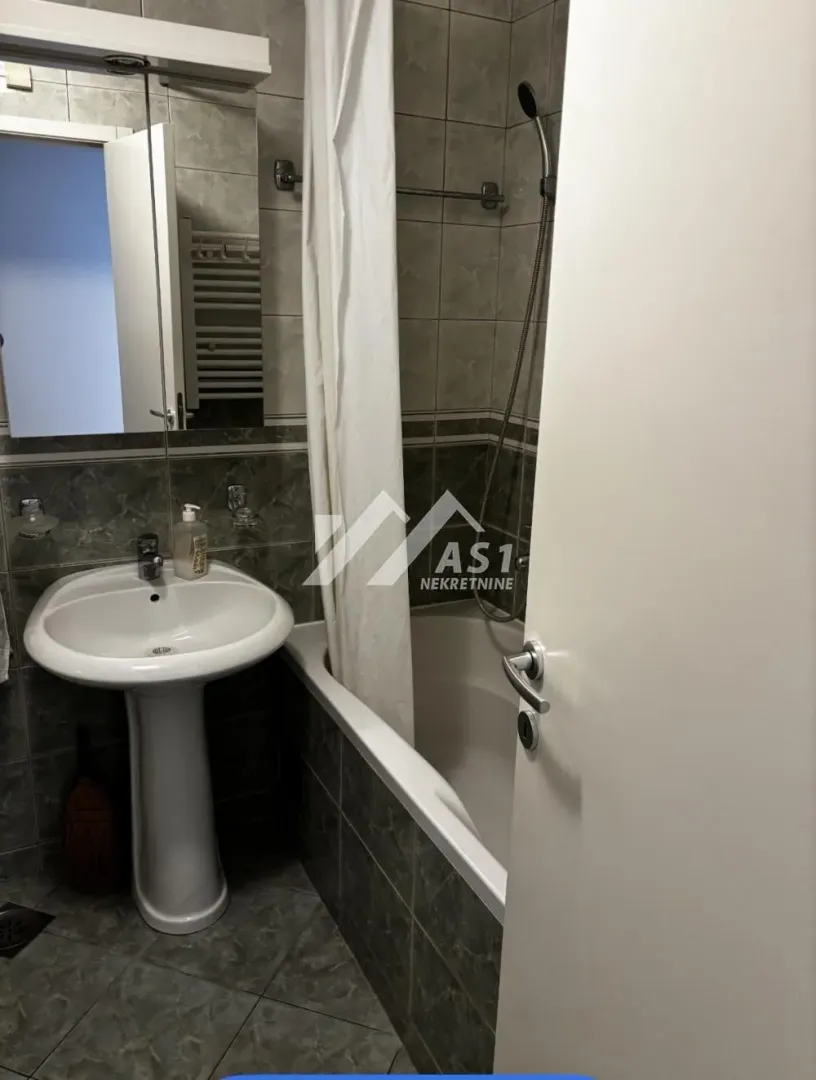 Bathroom with a washbasin, mirror, and bathtub with a curtain.
