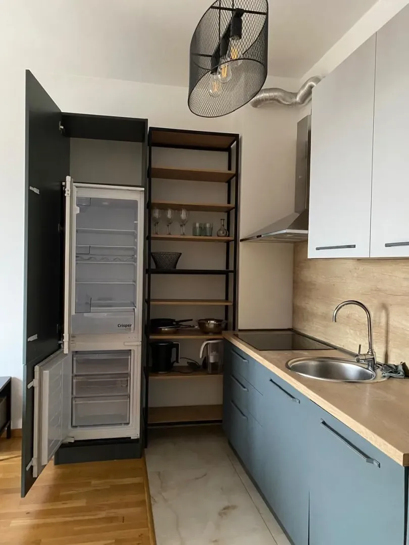 Moderna kuhinja sa bijelim i tamnim elementima i otvorenim policama.
