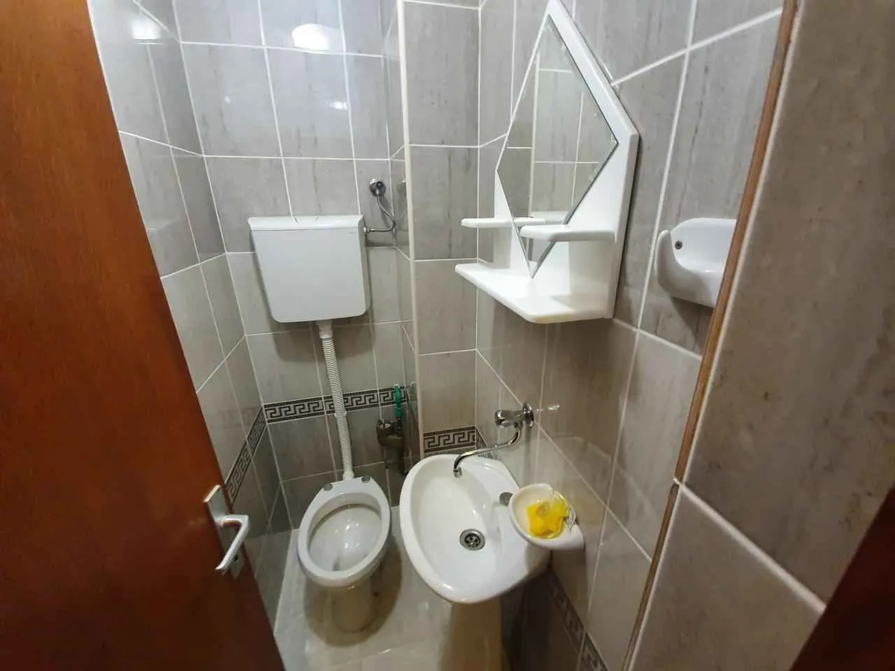 Manje kupatilo sa sanitarijama i pločicama u sivoj boji.