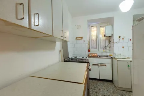 Starija kuhinja sa bijelim elementima, šporetom i manjim sudoperom pored prozora. - image 12