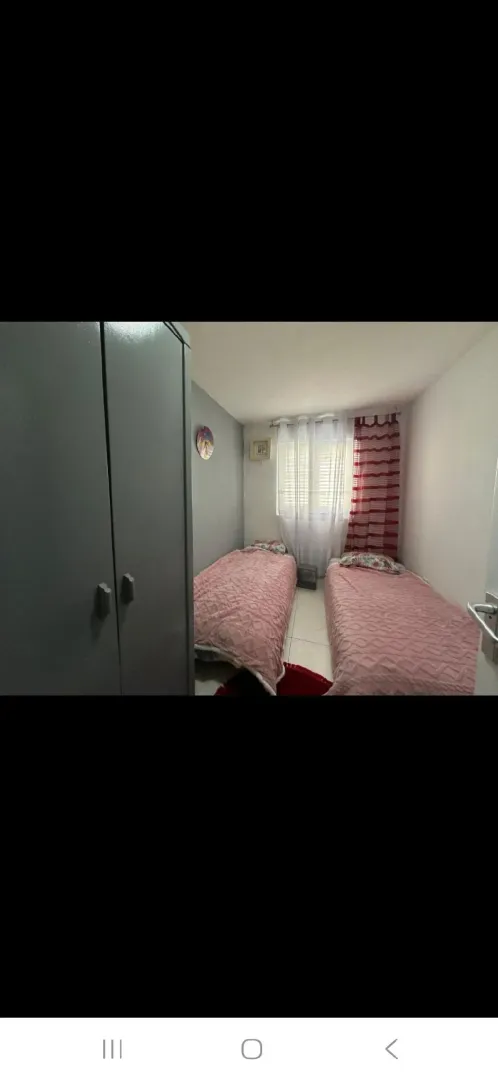Manja spavaća soba sa dva kreveta i ormarom.