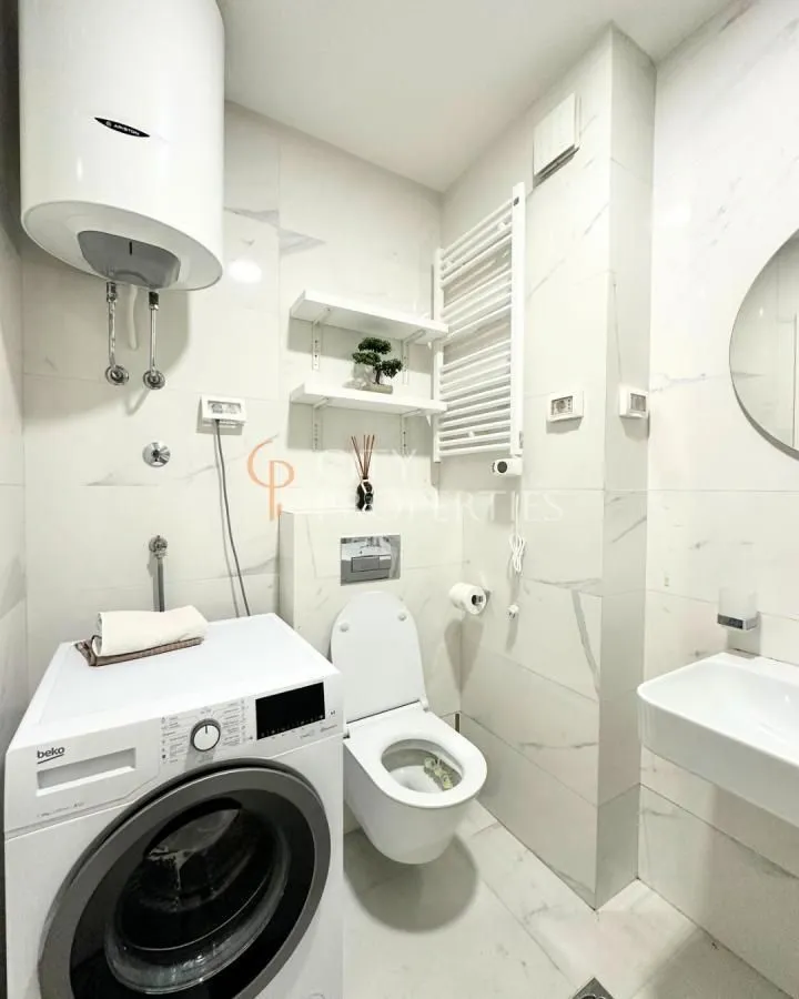 Moderne kupatilo opremljeno sanitarijama, tuš kabinom i mašinom za veš.