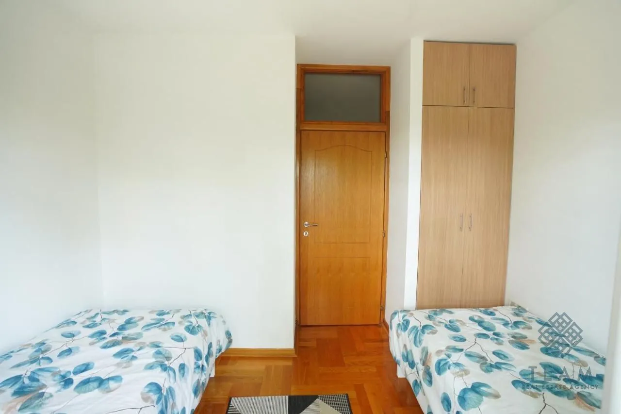 Bedroom with two beds, wooden wardrobe, and parquet flooring.