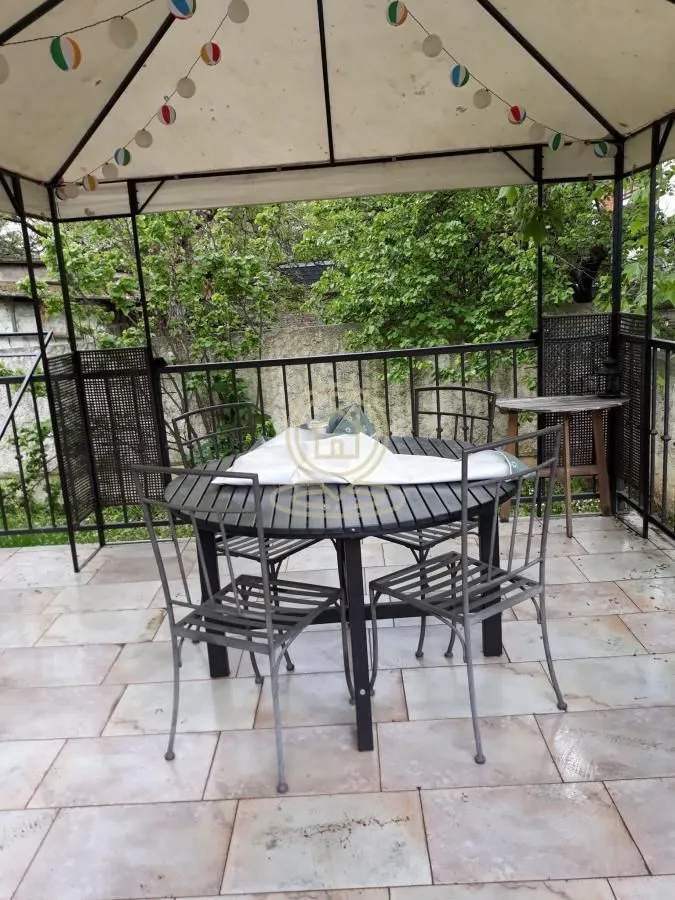 Covered gazebo with a table and chairs in the yard.