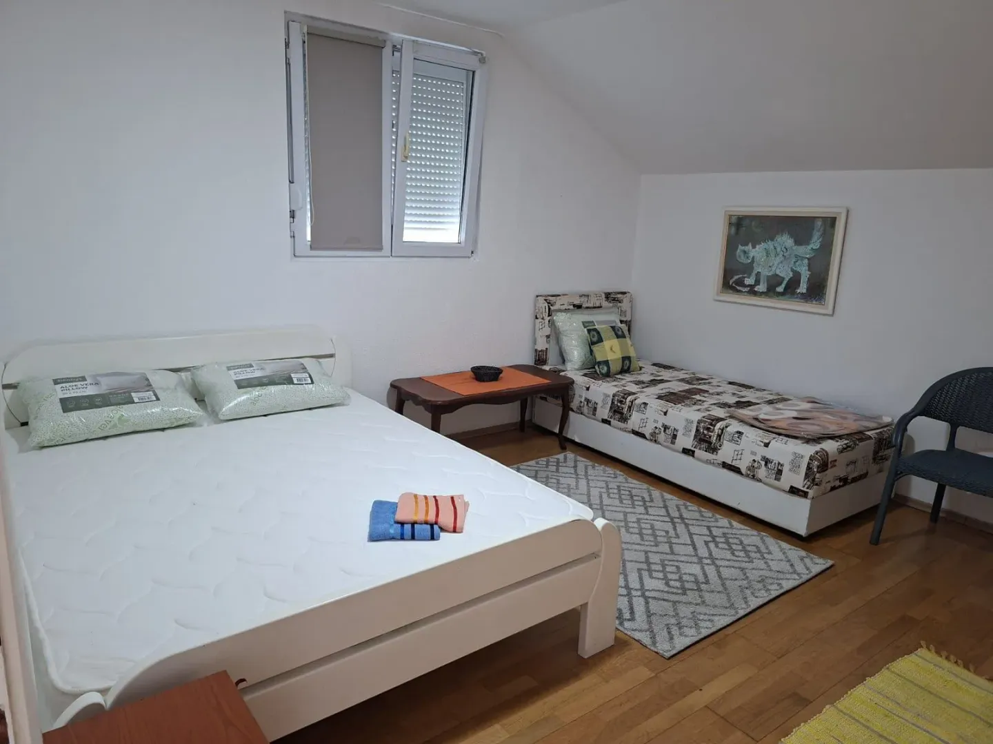Attic bedroom with two beds and white walls.